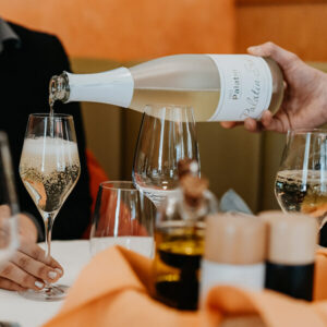 Es wird an einem eingedeckten Tisch Sekt eingeschenkt