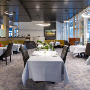 Das obere Restaurant offener Raum mit grauen Tischdecken und schwarzen Lederstühlen